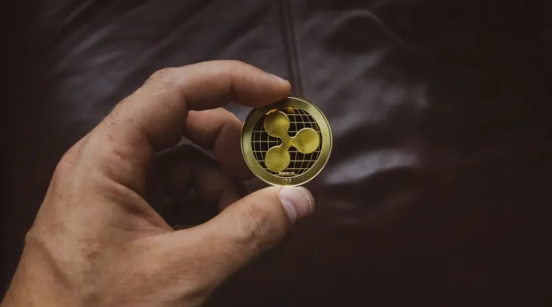 A hand holding a physical Ripple coin.
